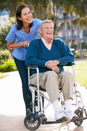 A nurse pushes an elderly man in a wheelchair